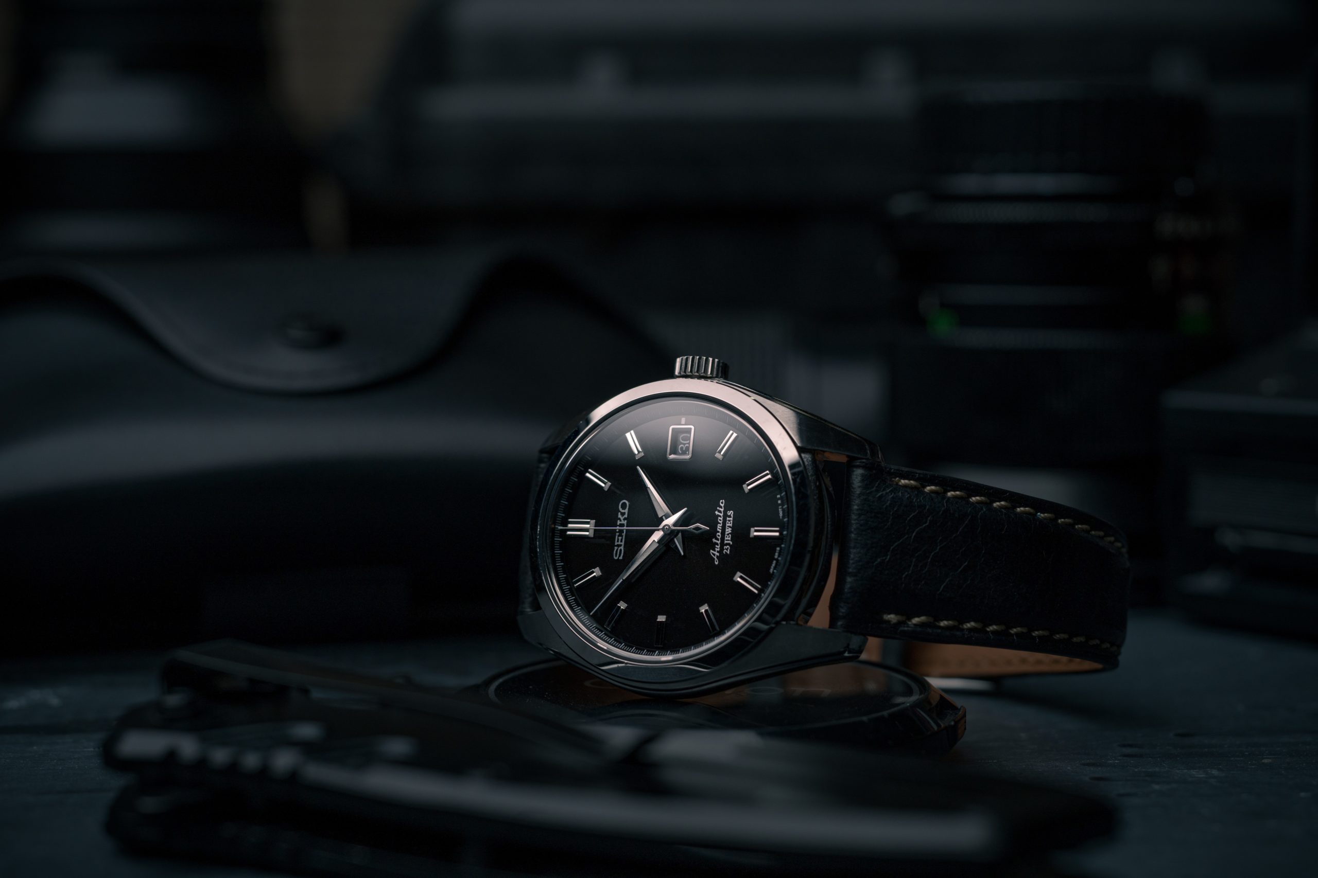 The image is a photograph of a wristwatch. It is a black Seiko Presage watch with a black leather strap. The image is a photograph of a wristwatch. It is a black Seiko Presage watch with a black leather strap.